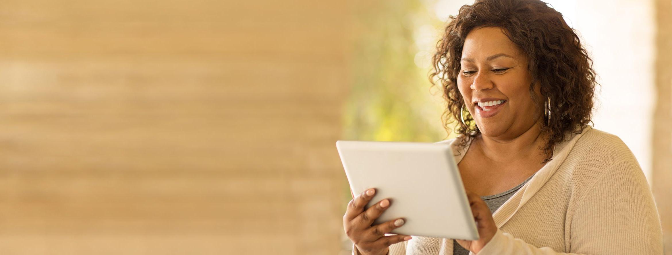 A woman pays her bills from her tablet with Patelco Online.